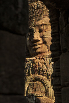 Bayon stone face revealed through temple shadows
