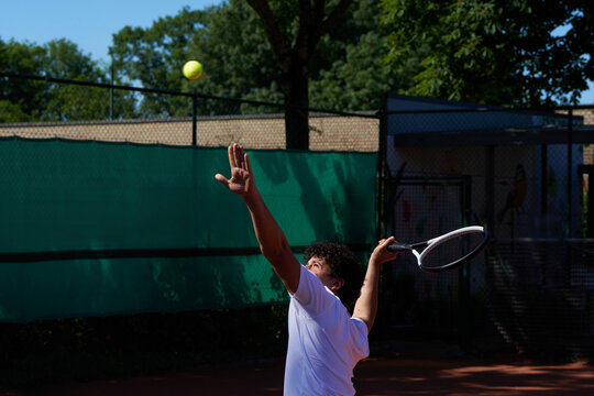 Player Serves Tennis Ball at a Local Court During the Day