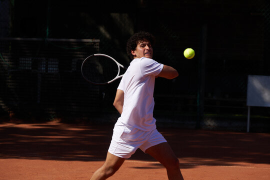 Young Man Plays Tennis on Outdoor Court During Sunny Day