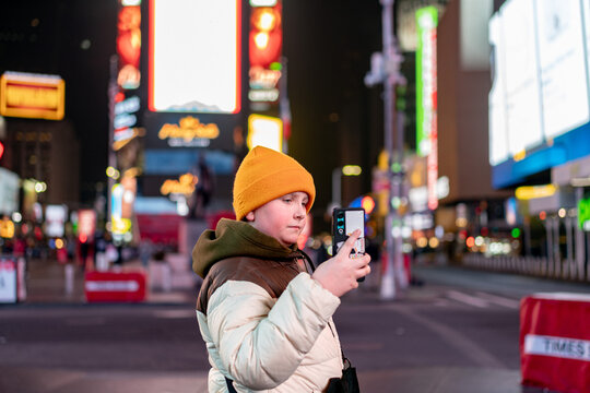 holding phone in neon-lit cityscape of Times Square New York

