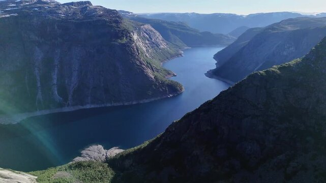 Drone perspective over deep blue fjord framed by steep cliffs and rugged Norwegian highlands near Trolltunga.