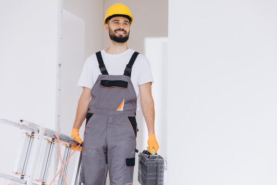 Smiling construction worker carrying a ladder and toolbox, ready for home renovation or repair work