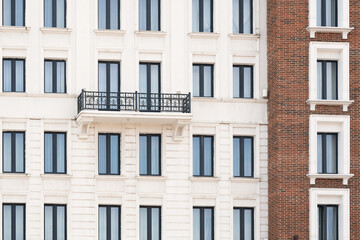 Fototapeta premium A modern neoclassical building facade featuring repeated black frame windows and a black wrought iron balcony.
