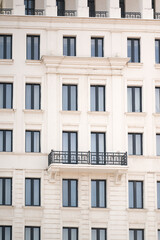 Fototapeta premium A modern neoclassical building facade featuring repeated black frame windows and a black wrought iron balcony.