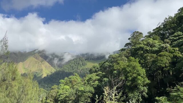Scenic view of green mountains and clouds under blue sky.