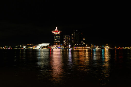 AMSTERDAM, NETHERLANDS - OCTOBER 30, 2025: A panoramic night view across the IJ river of the illuminated Amsterdam North skyline featuring the Eye Filmmuseum and A'DAM Lookout tower