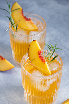 Peach and rosemary iced tea cocktail in glasses on a gray background. top view