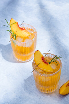 Peach and rosemary iced tea cocktail in glasses on a gray background. top view