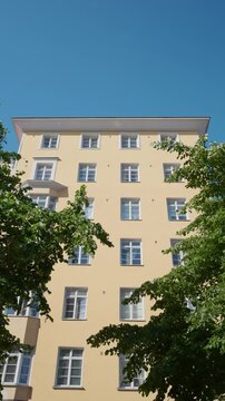 Sunlit yellow residential building framed by leafy green trees