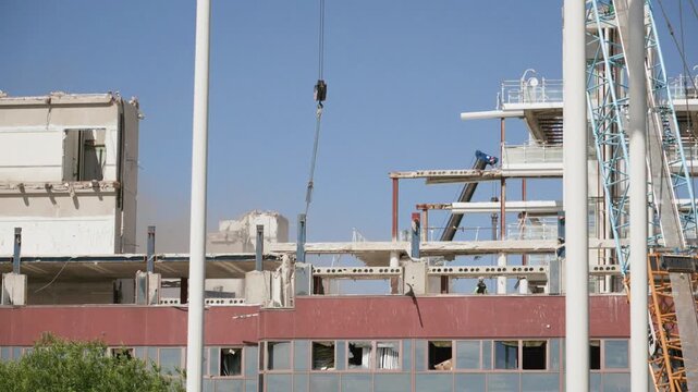 Industrial building demolition with crane machinery and rising dust