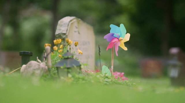 Colorful pinwheel memorial decoration beside flowers and gravestone