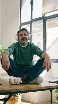 Video of mature man listening to music with headphones while sitting at the table at home