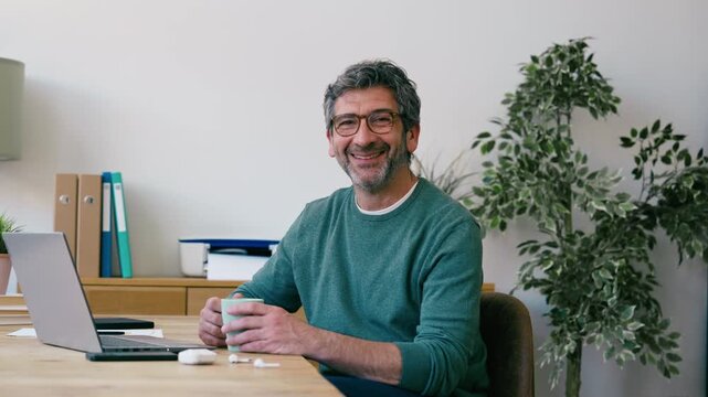 Video of mature man taking a break of work while drinking a cup of coffee at the office
