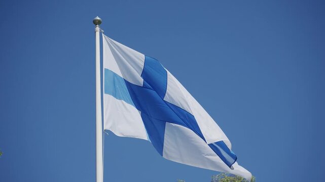 Finnish national flag waving against deep blue summer sky