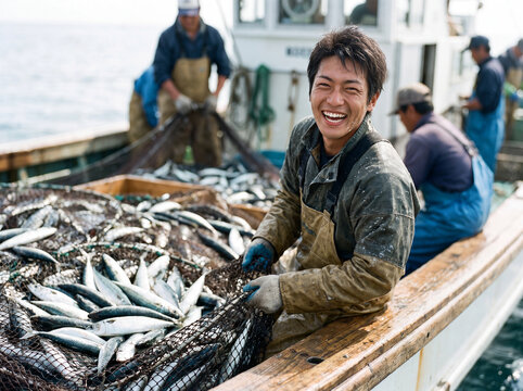 大漁の網を引き揚げ、船上で満面の笑みを浮かべる若い漁師