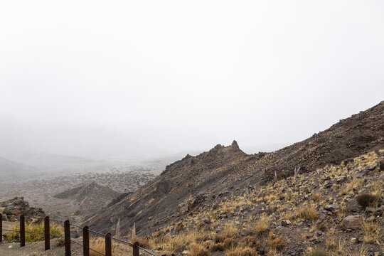 Volcanic landscape with arid terrain and rocky slope on a foggy day at mount teide