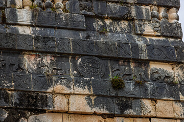 Close up of the dark stone relief carvings with jaguar figures and spiral patterns on the Jaguar Temple wall in Chichen Itza, Mexico © simonmayer
