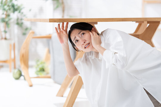 地震が起きてテーブルの下に隠れる女性