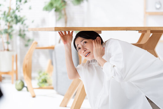 地震が起きてテーブルの下に隠れる女性
