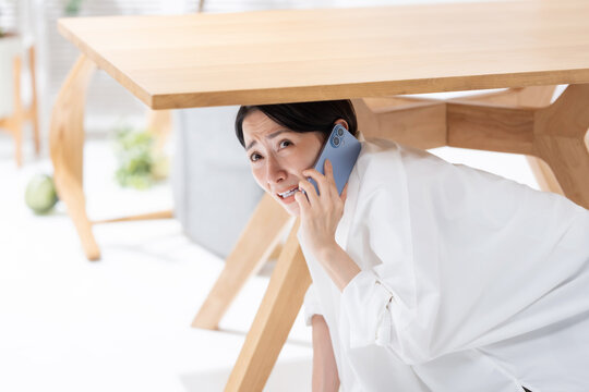 地震が起きてテーブルの下に隠れる女性