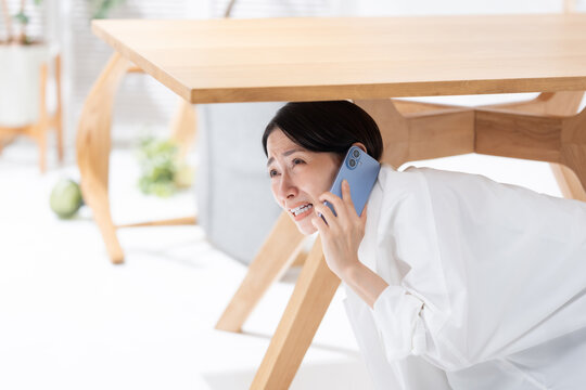 地震が起きてテーブルの下に隠れる女性