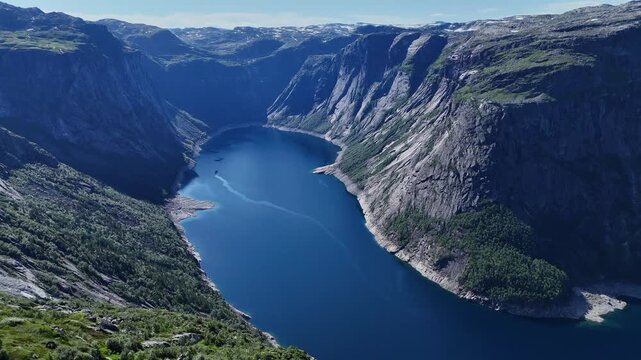 Drone panorama of deep blue fjord framed by steep cliffs and green slopes near Trolltunga in summer light.