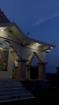 Illuminated Hindu Temple with Durga Mural and Red Flag at Dusk
