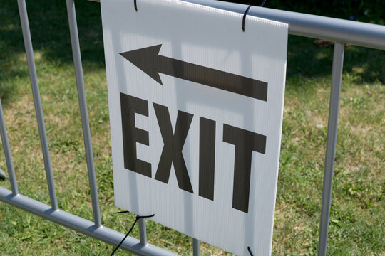 arrow and exit sign attached to a crowd control fence in the park