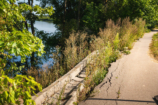 an asphalt road closed to traffic, which has been undercut by the Bug River