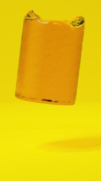 Crude oil filling a rotating gold metal barrel on a yellow background for petroleum industry concept. Vertical video.