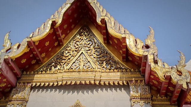 Ornate Golden Temple Gable With Intricate Carvings And Red Decorative Eaves