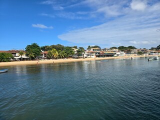 Fototapeta premium Panoramic view of Armacao beach coastline with waterfront houses, tropical trees and calm sea in Armacao dos Buzios, Rio de Janeiro, Brazil.