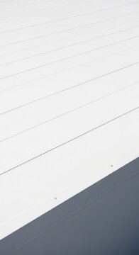 Superficie lisa de un techo plano protegido con una capa gruesa de aislante impermeabilizante de color blanco bajo la luz natural del sol, obra, acabado, recubrimiento