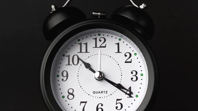 Vintage alarm clock at black background. Time lapse. Time running fast. Analog clock. Dolly slider. Table clock show running time. Close up in 4K, UHD