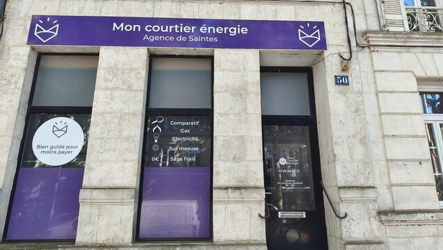 Saintes, France - April 21, 2026: Saintes. Mon courtier energie agency storefront with purple signage and glass doors, located in a stone building in a city setting