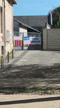 Saintes, France - April 21, 2026: Saintes. School entrance gate of Ecole Nicolas Lemercier with colorful vertical bars and concrete wall in a sunny outdoor setting