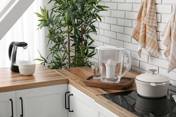 Fototapeta premium Modern kitchen interior with water filter pitcher, electric kettle, and cooking pot on wooden countertop