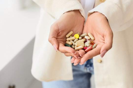 Womans hands holding a variety of colorful pills and capsules, health and wellness