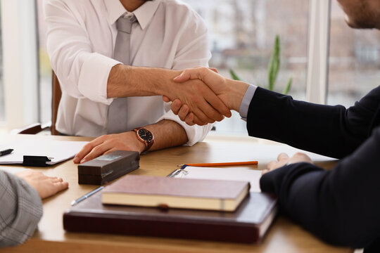 Male business mediator shaking hands with clients at table in office