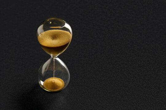 Hourglass with yellow crystals on black background. Time management concept