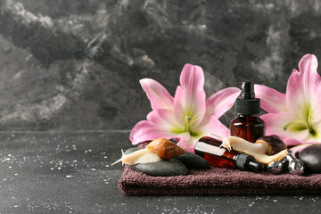 Composition with giant Achatina snails, spa accessories, cosmetic products and lily flowers on grunge background © Pixel-Shot
