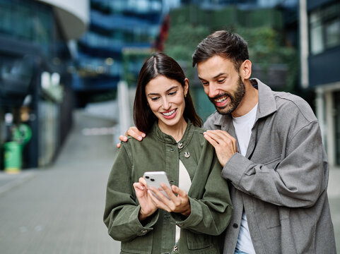 Couple enjoys a sunny day walking together in a charming urban area during late afternoon or tourists visiting a destination  looking at phone map app