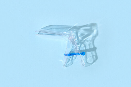 Gynecological speculum on light blue background, top view