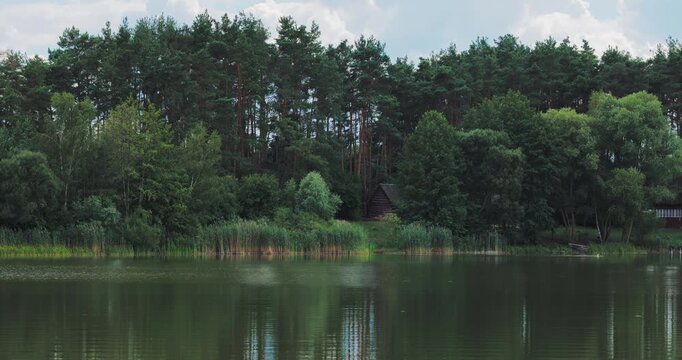 Scenic landscape with a calm river water reflection and wooden cabin