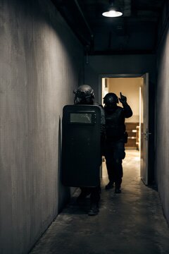 Two swat team soldiers in black tactical uniform with body armor conducting a raid. Special task force entering a corridor for operation.