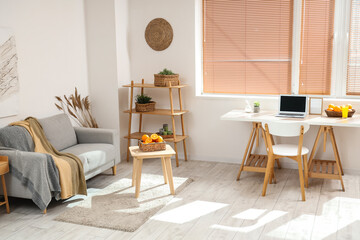 Fototapeta premium Wicker basket with citruses on coffee table near sofa in white living room