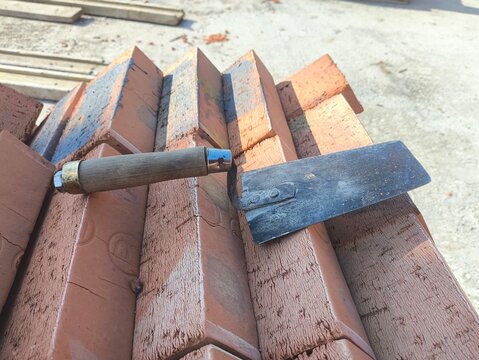 Bricklaying trowel resting on masonry bricks at a construction site. Hand tool for brickwork and masonry. Horizontal photo.