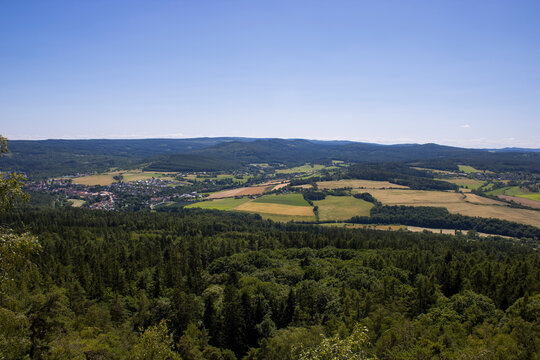 A breathtaking panoramic view from Čertova kazatelna overlooking rolling forests, peaceful villages and patchwork fields stretching across the Czech countryside beneath a clear summer sky.
