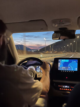 Man driving car on coastal highway navigating with GPS in evening, exploring scenic Makarska, Croatia, during road trip travel experience at sunset