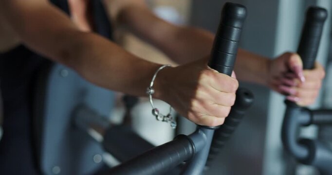Close up of female hands holding handles of a gym fitness machine